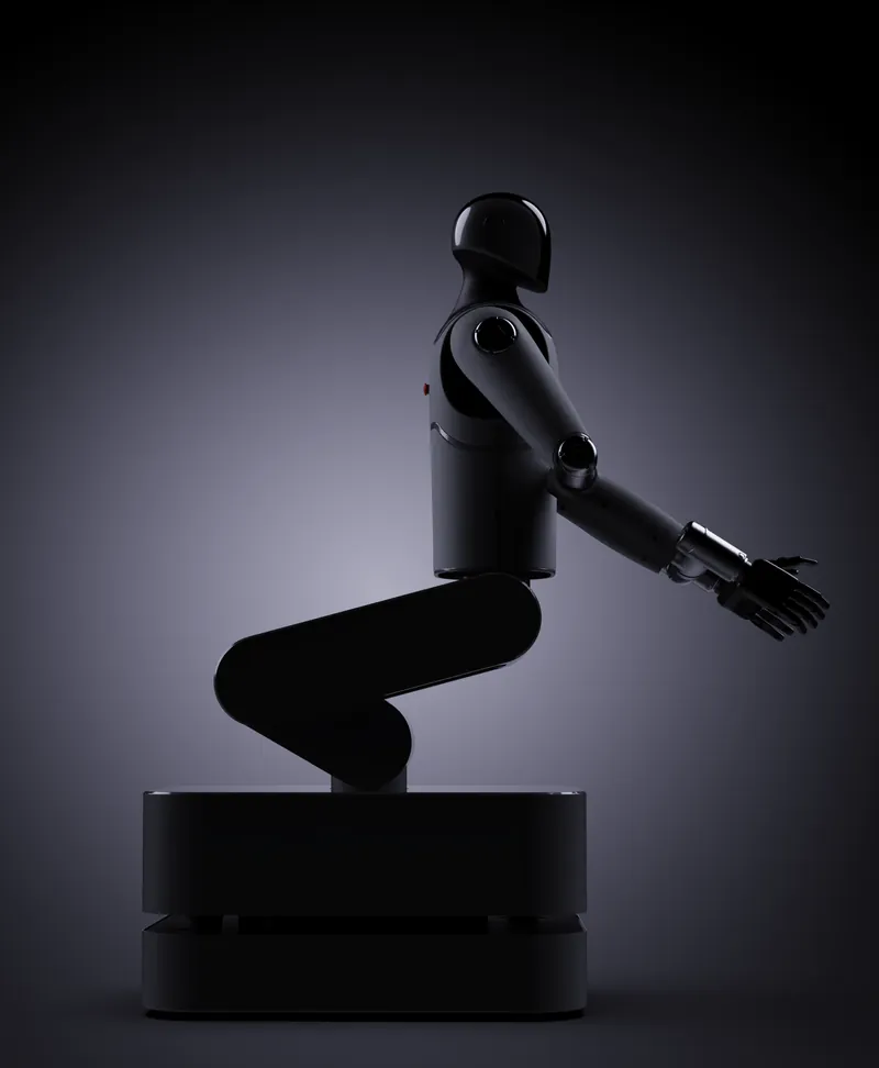 MARK One seated on its base in a dark studio, arms reaching forward